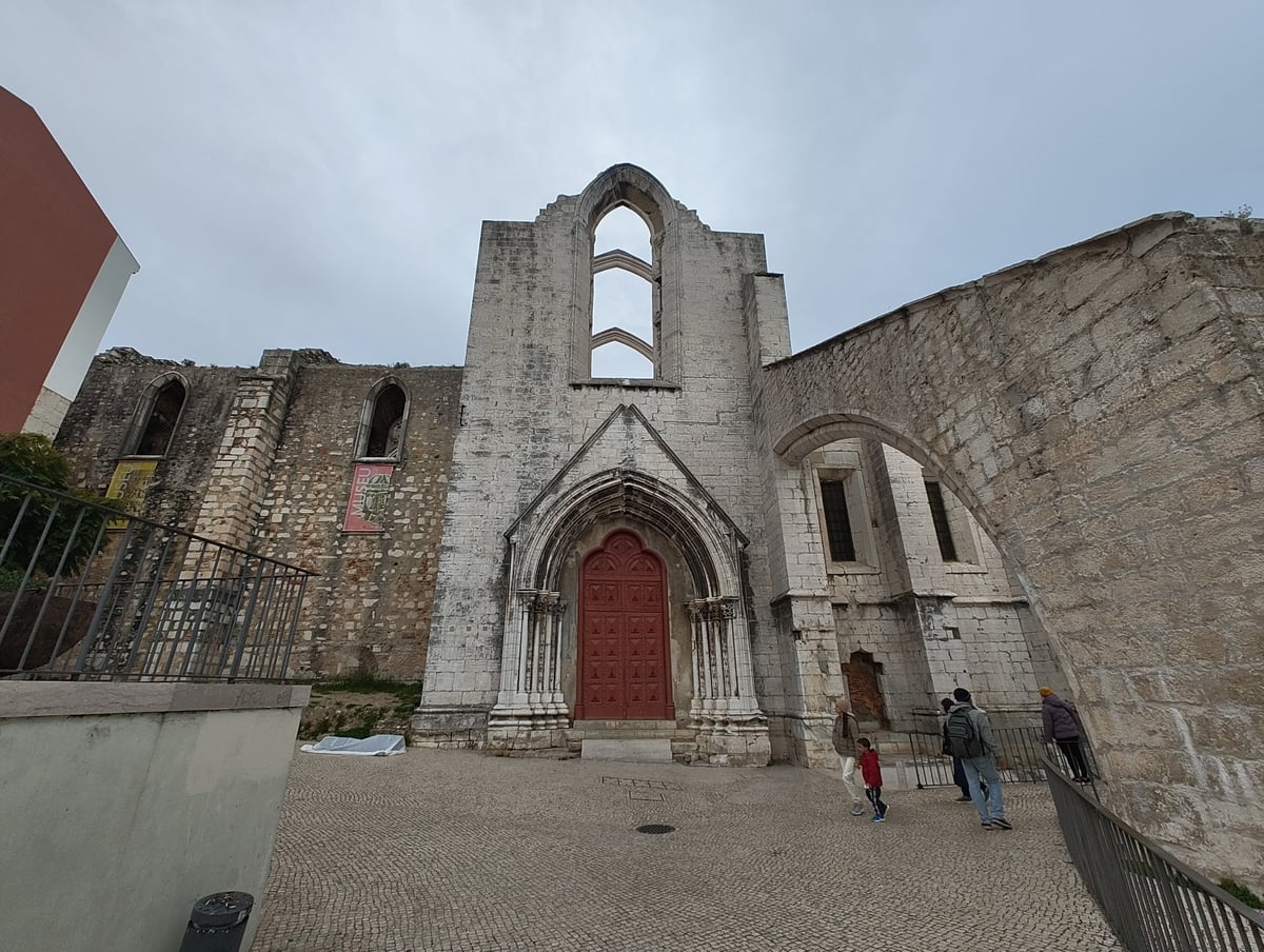 Los arcos góticos del Convento do Carmo de Lisboa abiertos al cielo, sin techo desde el terremoto de 1755, con la luz entrando entre las columnas.