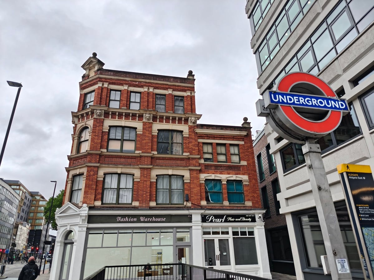 Un edificio victoriano de ladrillo rojo en Aldgate East, con el logotipo del metro de Londres en primer plano