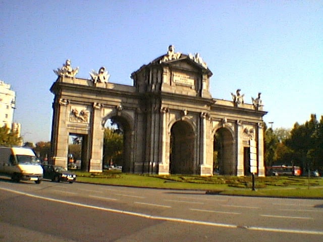 La Puerta de Alcalá con sus cinco vanos y el escudo real sobre el arco central, en medio de la Plaza de la Independencia.