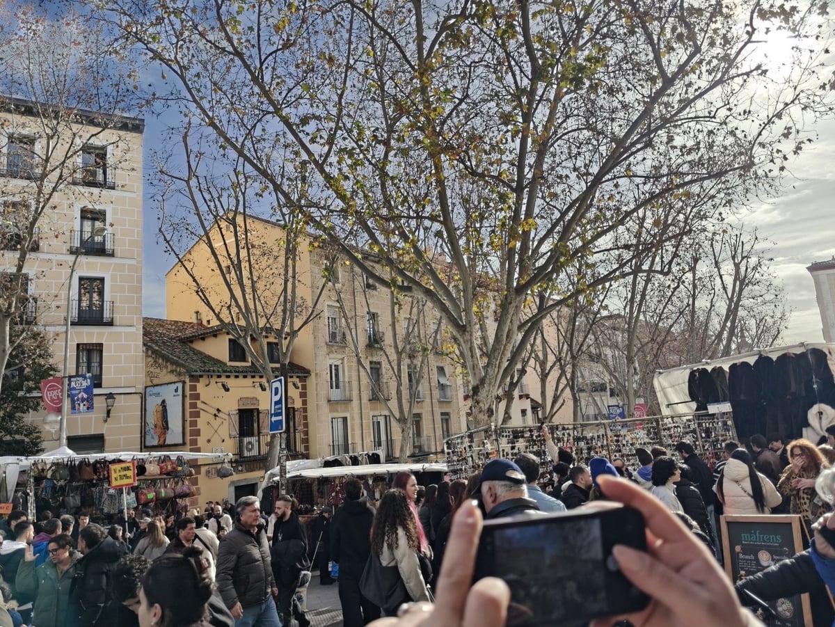 Ambiente dominical en el Rastro de Madrid, con puestos y gente paseando entre ellos.