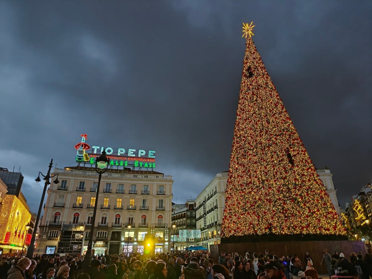 La Puerta del Sol de Madrid abarrotada de gente con el árbol de Navidad en primer plano.