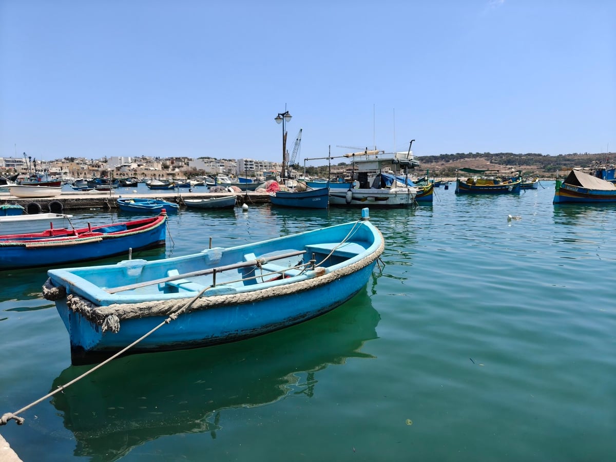 El paseo marítimo de Marsaxlokk con los luzzus de colores amarrados frente al mercado dominical.