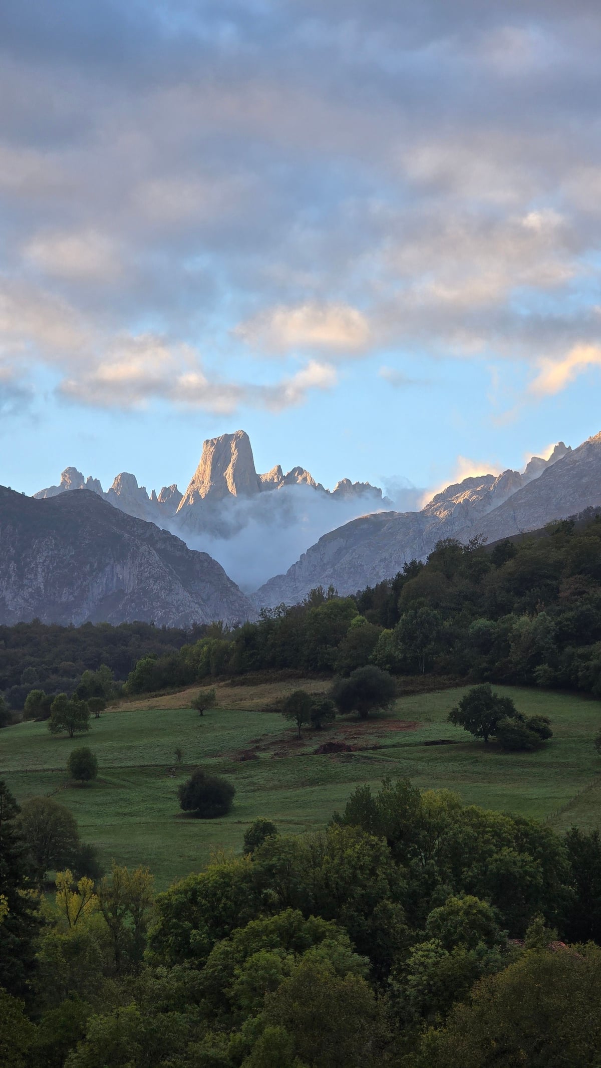 Cautivadora vista de escarpados picos de montañas bajo un cielo nublado con un exuberante valle verde.