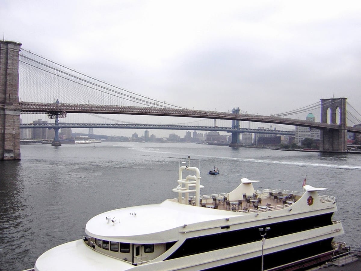El puente de Brooklyn visto desde el Pier 17, con sus torres neogóticas de piedra y el entramado de cables suspendidos sobre el agua.