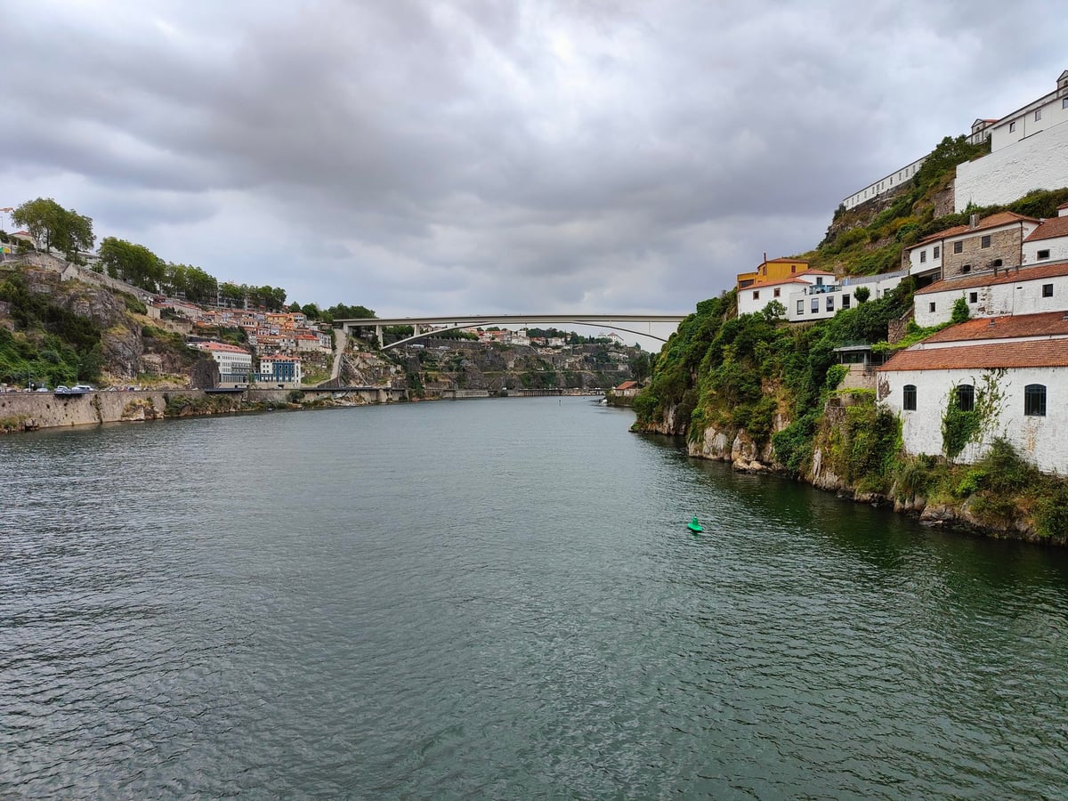 Panorámica del centro histórico de Oporto con las fachadas de la Ribeira bajando hacia el Duero, los barcos rabelos amarrados y el puente Luis I cruzando el río.