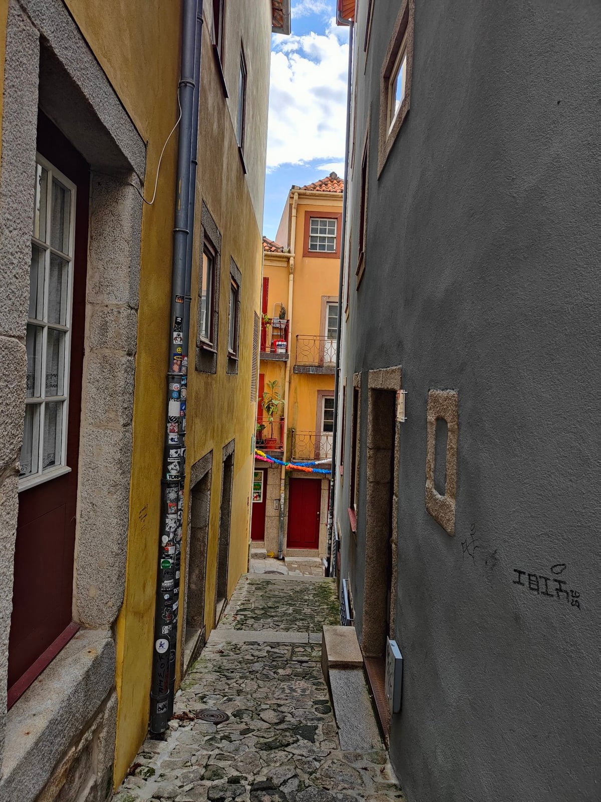 Fachadas de edificios tradicionales de Oporto revestidas de azulejos y con balcones de hierro forjado, en una calle en cuesta del centro histórico.