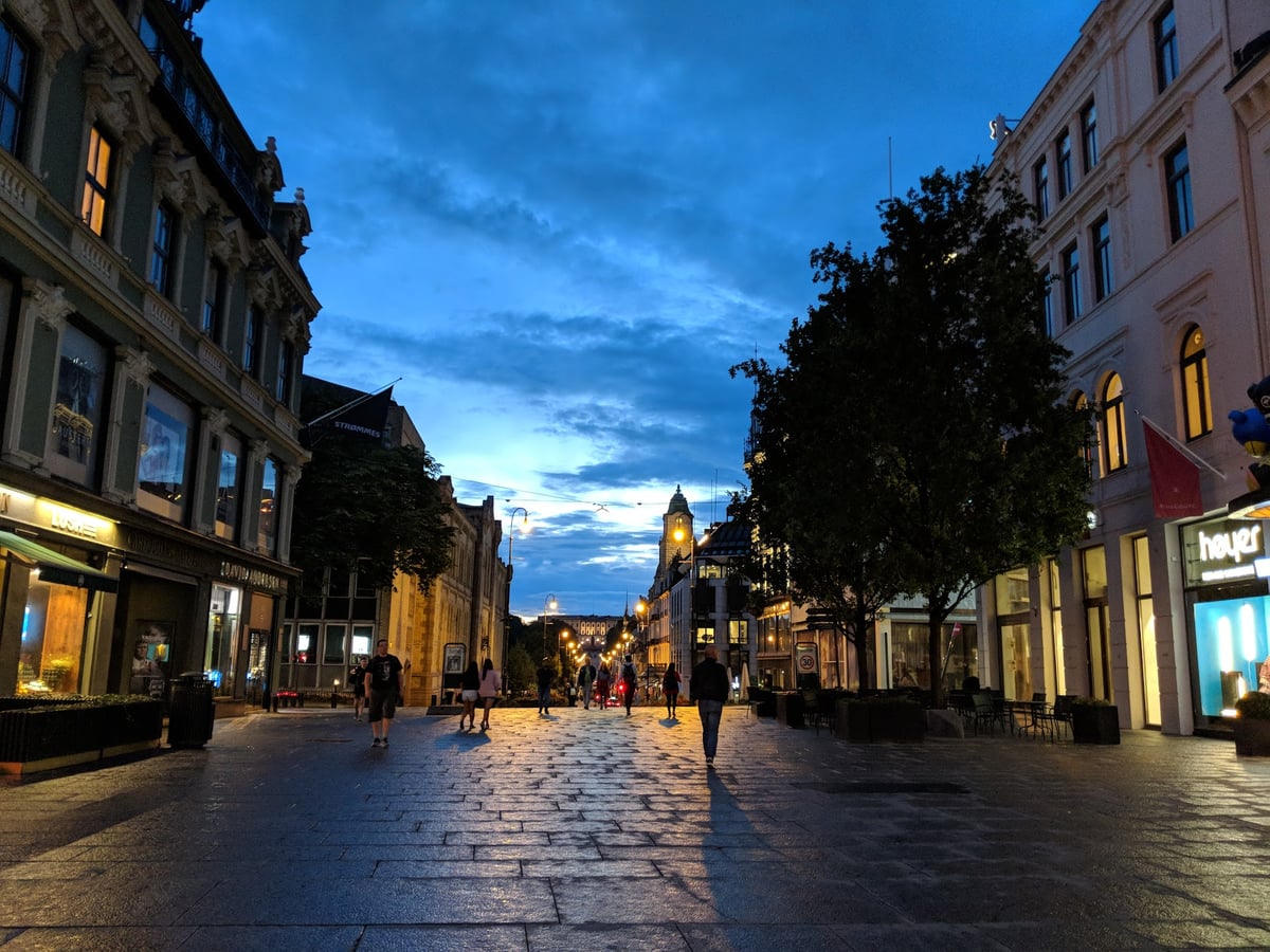 Karl Johans gate al anochecer, con las farolas encendidas y el paseo peatonal hacia el Palacio Real