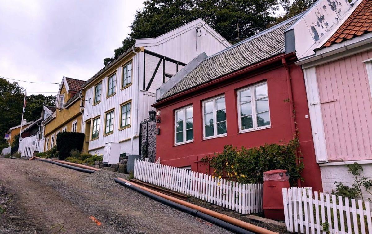 Casas de madera de colores en la cuesta empedrada de Damstredet, con vallas blancas y jardines pequeños