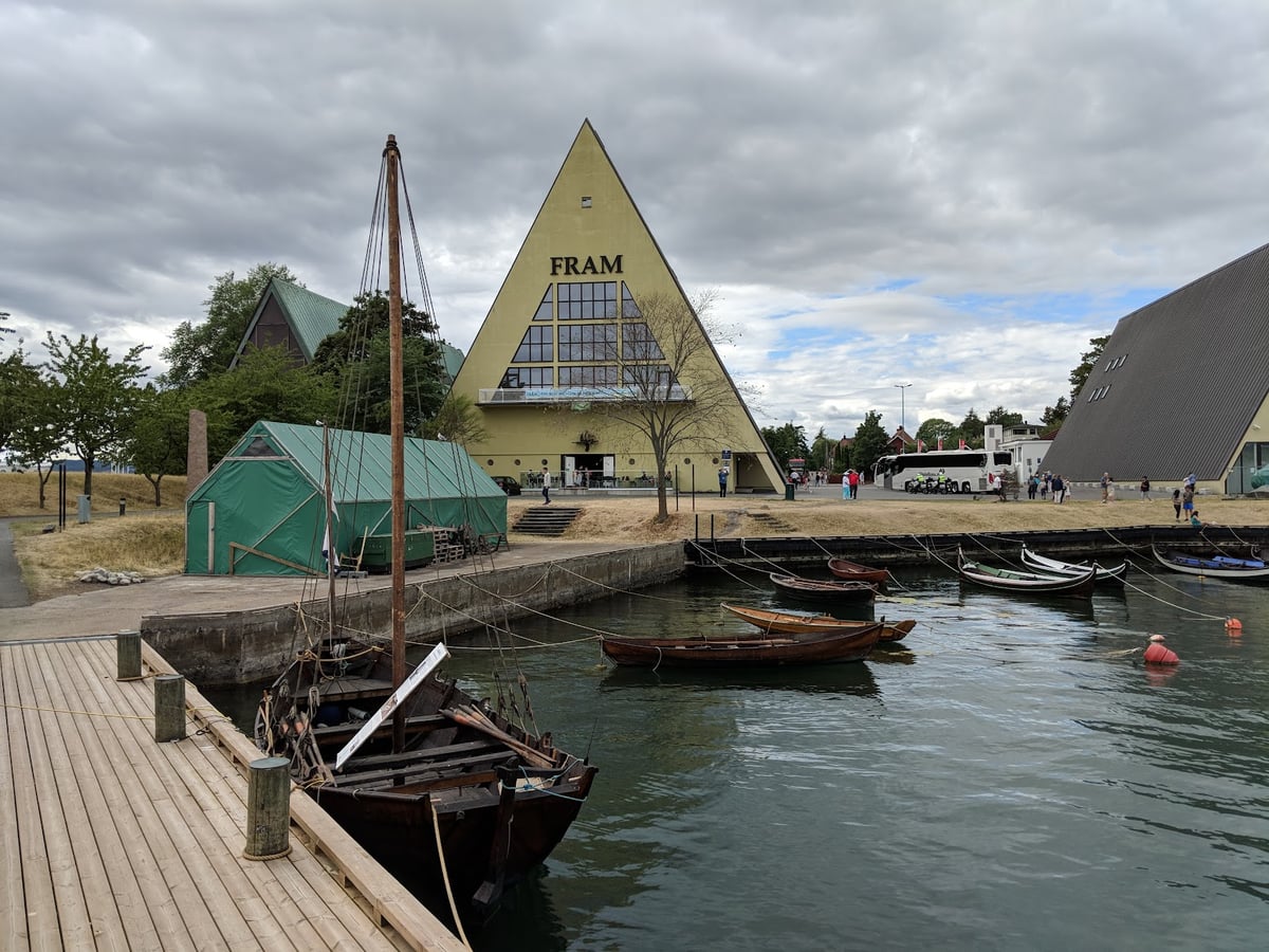 La fachada triangular y amarilla del Museo Fram, junto al muelle donde amarran las barcas de madera, en Bygdøynes
