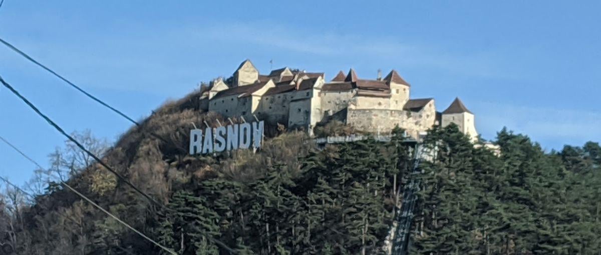 El letrero de RÂȘNOV en letras blancas sobre la ladera de la montaña, visto desde la carretera