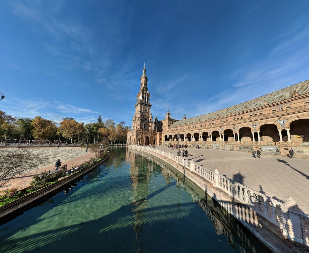La Plaza de España de Sevilla, con la torre norte reflejada en el canal y la galería de arcos a un lado