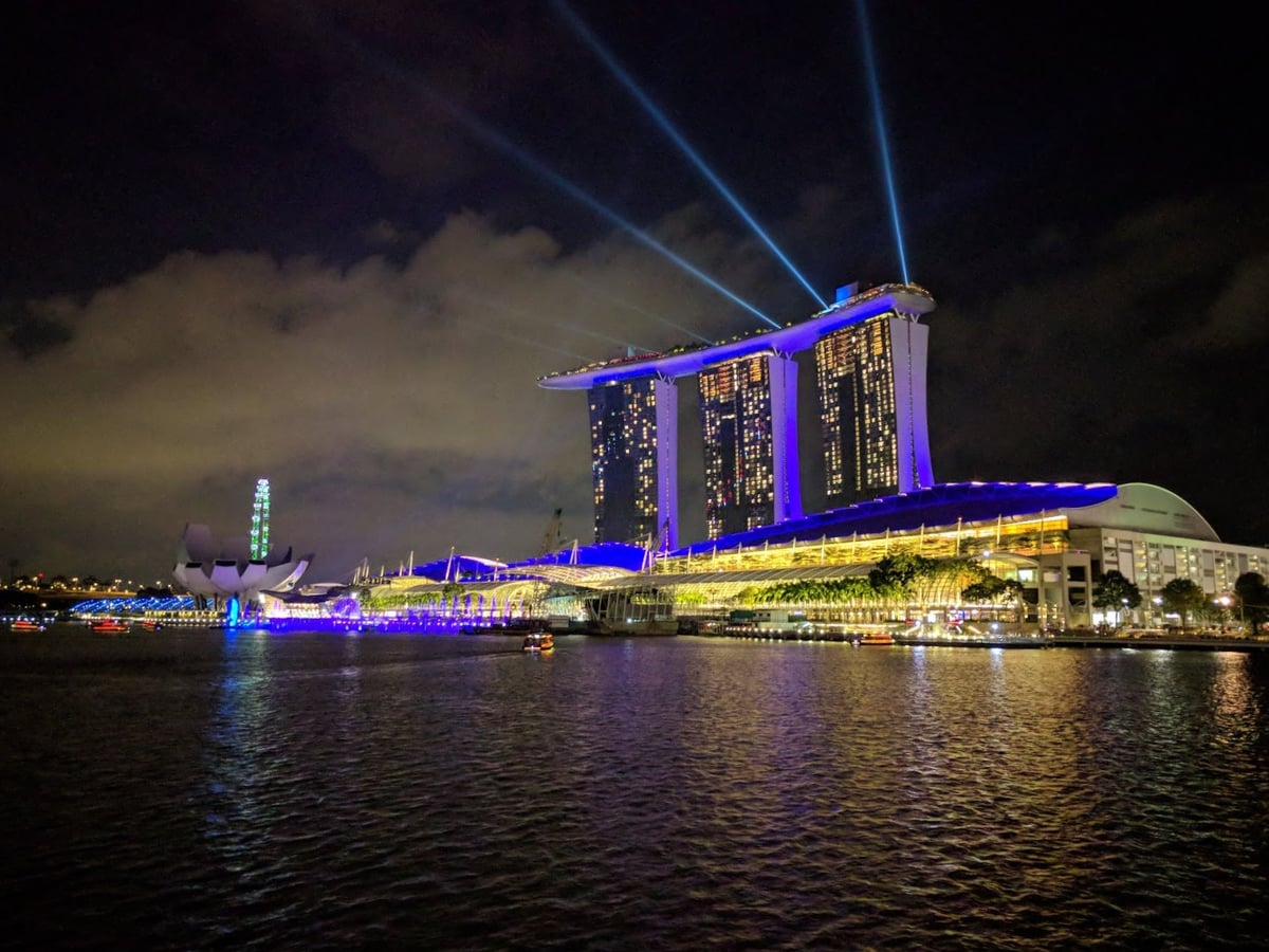 Vista nocturna de Marina Bay en Singapur con edificios iluminados y reflejos en el agua