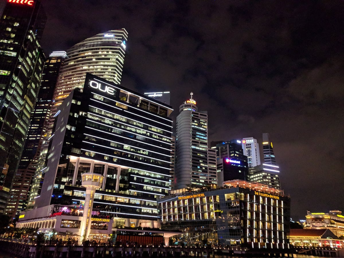 Vista nocturna de Marina Bay en Singapur con edificios iluminados y reflejos en el agua