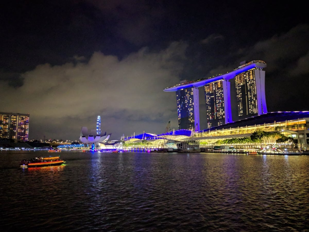 Vista nocturna de Marina Bay en Singapur con edificios iluminados y reflejos en el agua