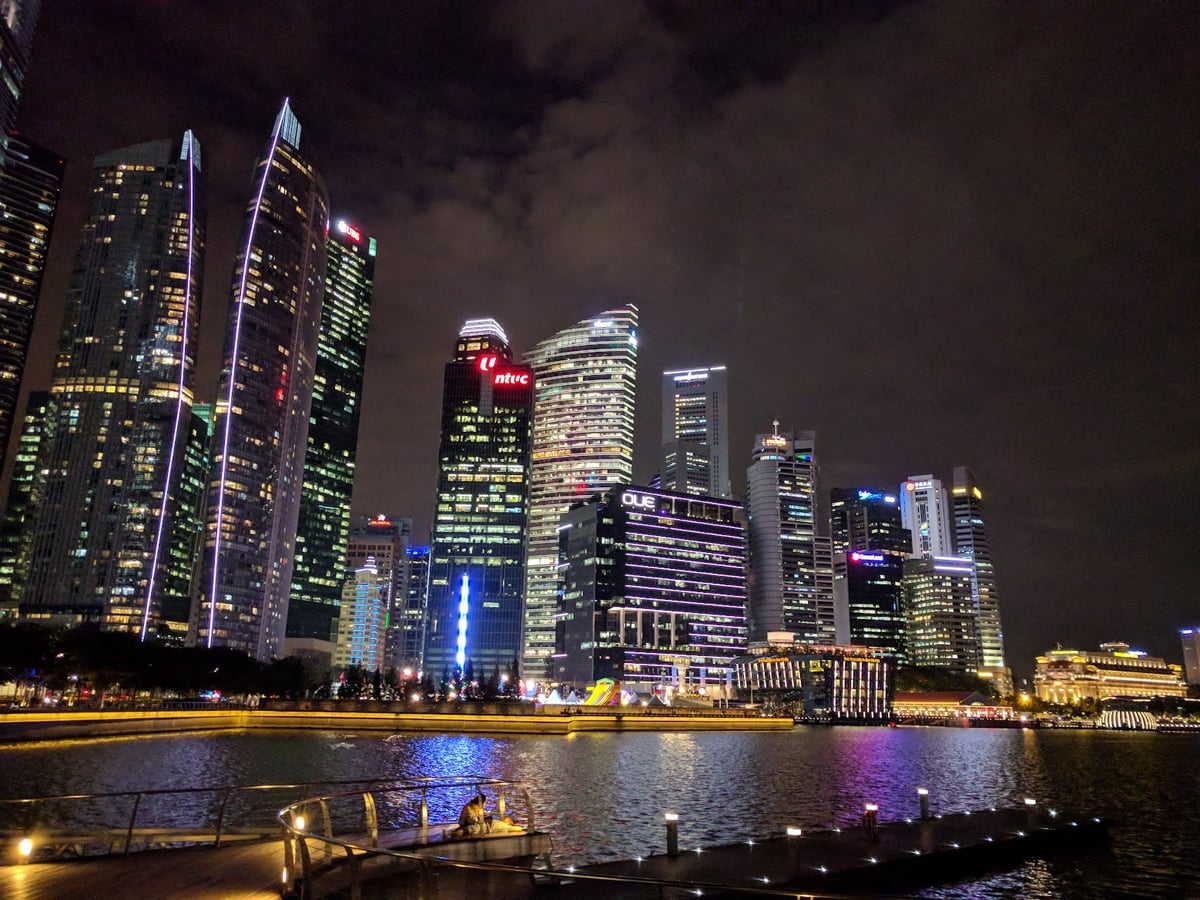 Vista nocturna de Marina Bay en Singapur con edificios iluminados y reflejos en el agua