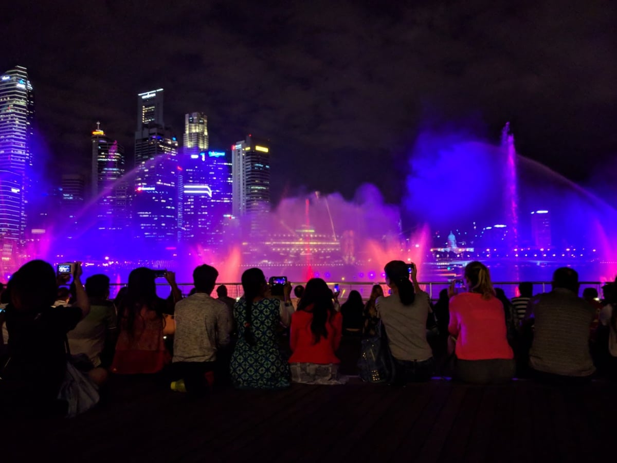 Vista nocturna de Marina Bay en Singapur con edificios iluminados y reflejos en el agua