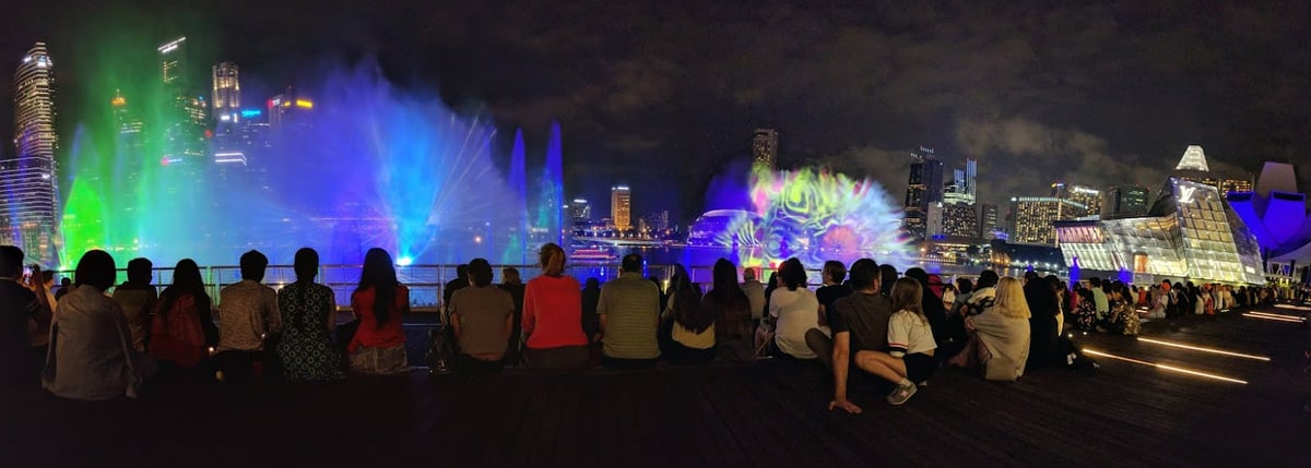 Vista nocturna de Marina Bay en Singapur con edificios iluminados y reflejos en el agua