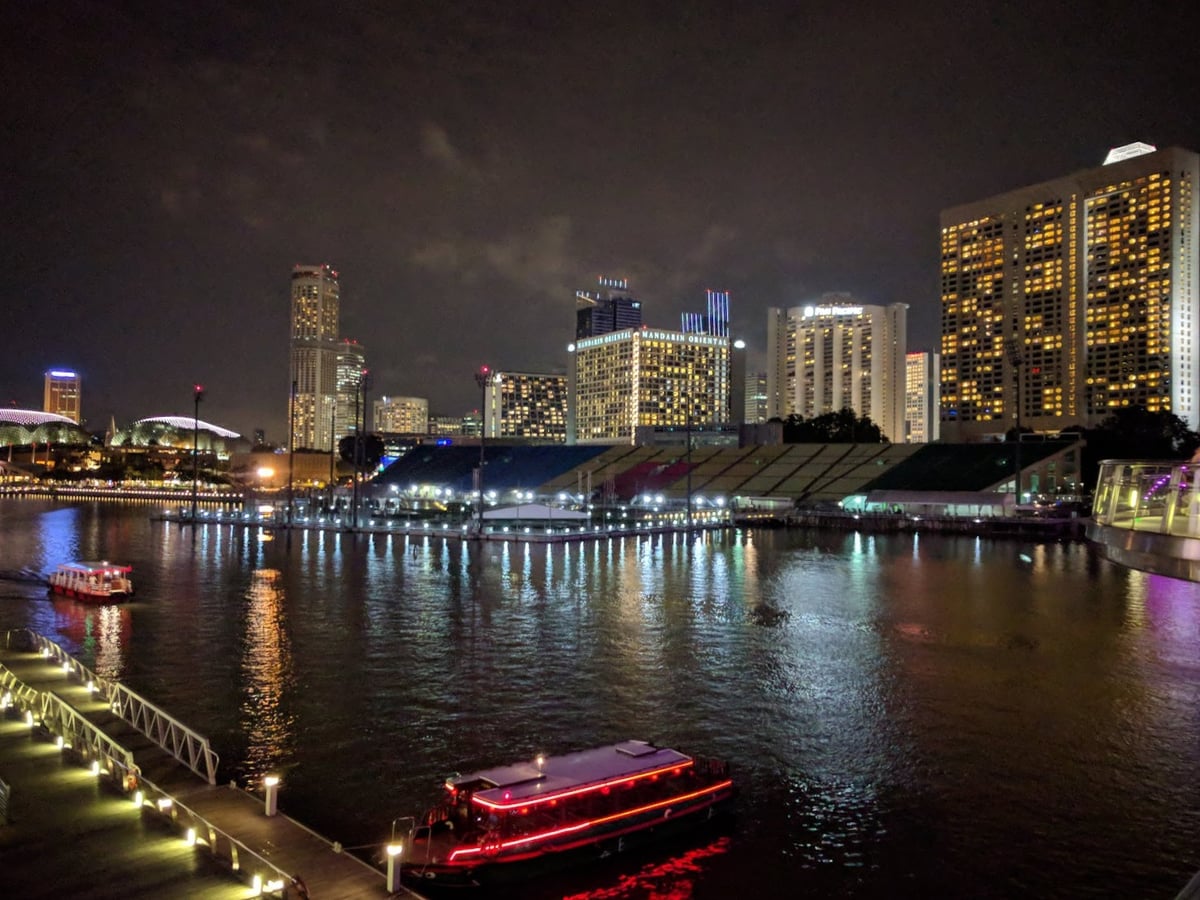 Vista nocturna de Marina Bay en Singapur con edificios iluminados y reflejos en el agua