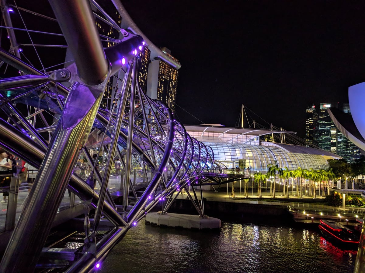 Vista nocturna de Marina Bay en Singapur con edificios iluminados y reflejos en el agua