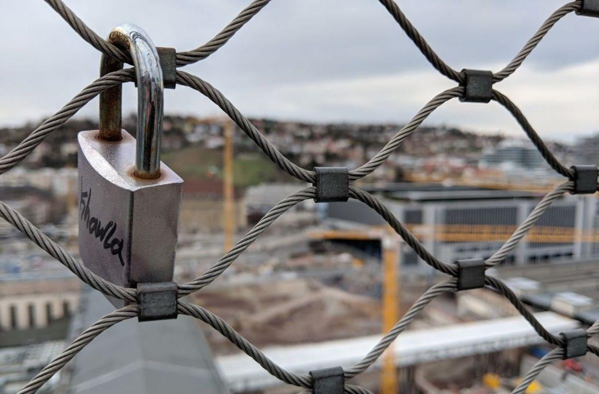 Detalle de una alambrada con un candado y vistas de Stuttgart al fondo