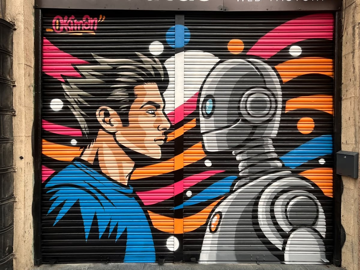 Mural terminado en la persiana de Idenautas: un hombre de perfil frente a un robot metálico sobre fondo negro con bandas rosas, naranjas y azules